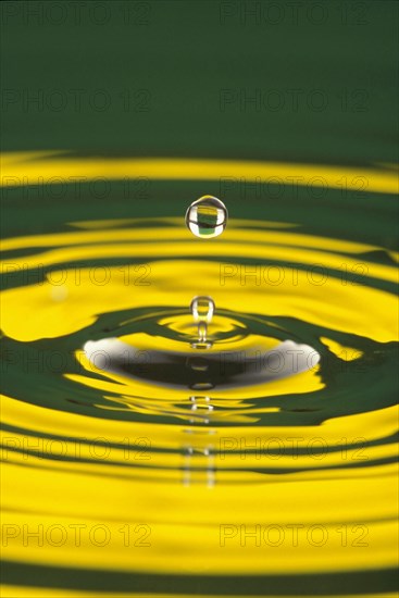 WATER, Drops, Pattern, Water droplet at moment of suspension above circular ripples with yellow colour reflected in water surface.