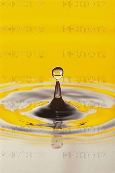 WATER, Drops, Pattern, Droplet of water meeting splash from surface with circular ripples and reflected yellow colour.