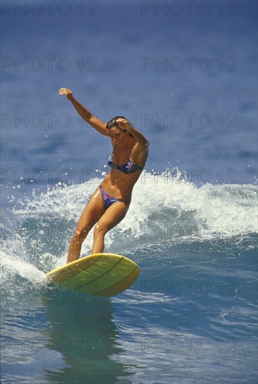SPORT, Sea, Surfing, "Woman surfer wearing bikini, riding small wave with both arms raised to aid balance."