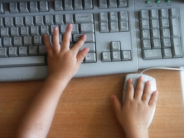 CHILDREN, Education, Computers, Cropped view of child using a computer showing hands on keyboard and mouse.