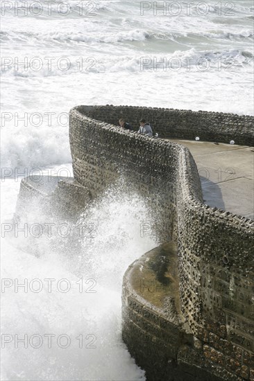 ENGLAND, East Sussex, Brighton, "Seafront, Tourists With waves crashing against sea defences."