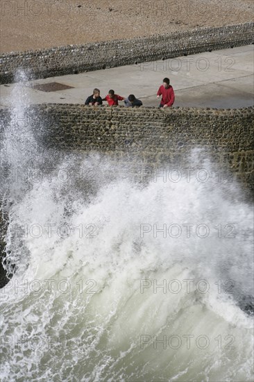 ENGLAND, East Sussex, Brighton, "Seafront, Tourists With waves crashing against sea defences."