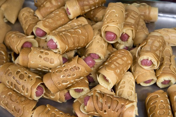 THAILAND, North, Chiang Mai, Close of small sausages wrapped in pancakes on sale in market. Pigs in blankets.