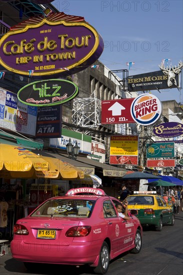 THAILAND, Central, Bangkok, Khaosan Road. Pink Taxi parked beneath colourful advertising signs.