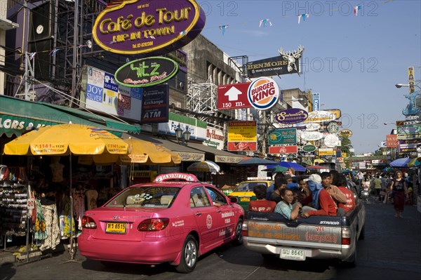 THAILAND, Central, Bangkok, Khaosan Road. Pink Taxi parked beneath colourful advertising signs.