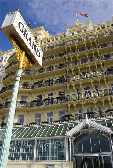 ENGLAND, East Sussex, Brighton, The De Vere Grand Hotel entrance and facade of rooms with balconies and sign on the seafront with a Union Jack Flag flying from a flagpole on the roof.