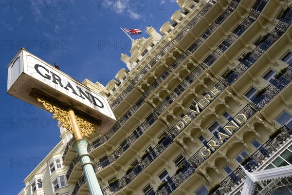 ENGLAND, East Sussex, Brighton, The De Vere Grand Hotel entrance and facade of rooms with balconies and sign on the seafront with a Union Jack Flag flying from a flagpole on the roof.