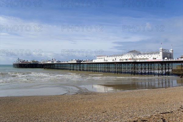 ENGLAND, East Sussex, Brighton, The Pier at low tide with shingle pebble beach in foreground.