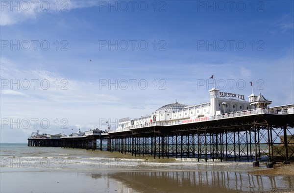 ENGLAND, East Sussex, Brighton, The Pier at low tide with shingle pebble beach in foreground.
