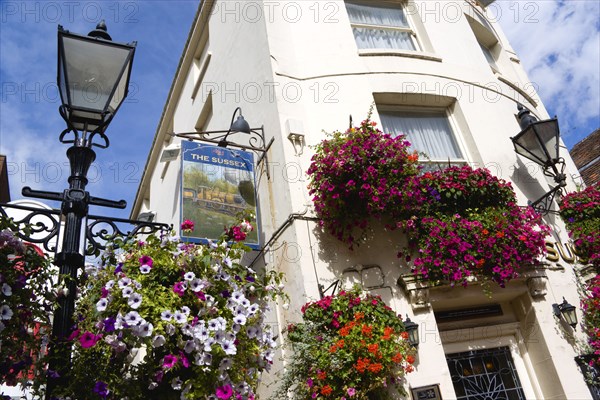 ENGLAND, East Sussex, Brighton, The Lanes Old fashioned streetlight lamppost outside The Sussex Pub with flowers in window boxes and hanging baskets.