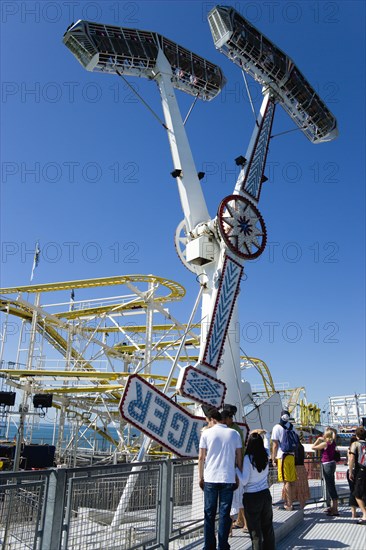 ENGLAND, East Sussex, Brighton, People watching the pendulum ride on Brighton Pier with the crowded passenger carrying gondolas in the air.