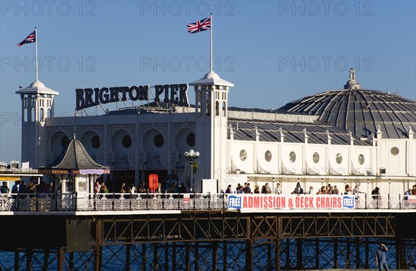 ENGLAND, East Sussex, Brighton, The Pier at low tide with people walking on the pier.