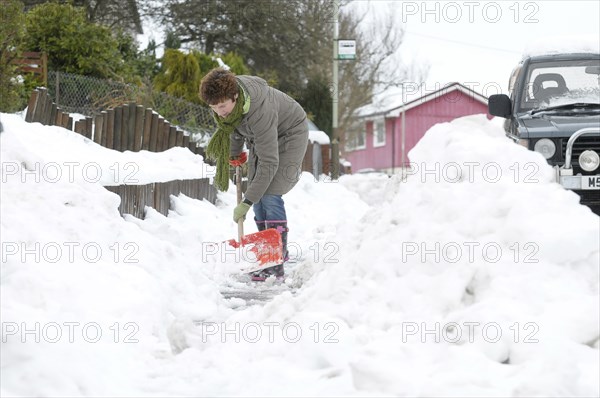 WEATHER, Winter, Snow, Snow scenes in Perth Scotland woman clearing snow from pathway with shovel during January 2010.