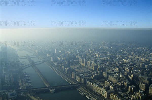 France, Ile de France, Paris, Aerial view over city and river through thick smog.