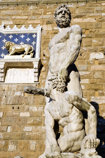 ITALY, Tuscany, Florence, The 1533 statue of Hercules and Cacus by Bandinelli seen through the legs of a stone lion outside the Palazzo Vecchio in the Piazza della Signoria.