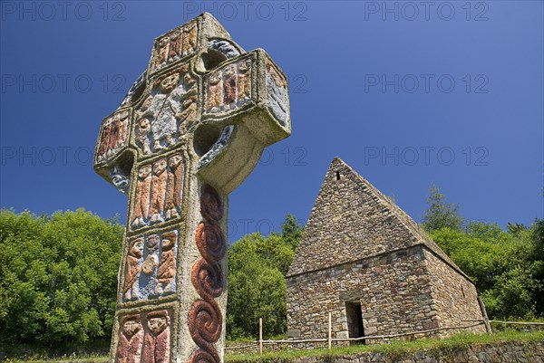 IRELAND, County Wexford, Irish National Heritage Park, Reconstruction of a typical monastic oratory with replica of a celtic cross in front.