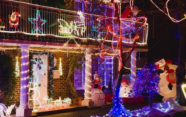 England, Buckinghamshire, Flackwell Heath, Detached house at Christmas time with decoration on the building and in the garden of lights and inflatable Santa Claus and Snowman.