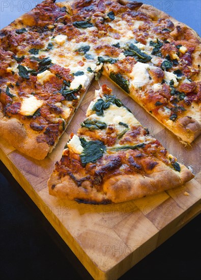 Food, Cooked, Pizza, Italian spinach and ricotta cheese pizza on wooden cutting board with a slice cut out.