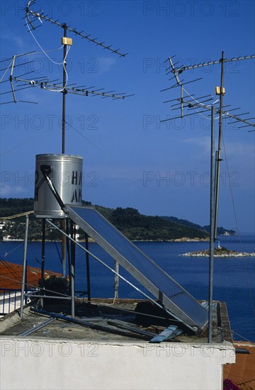 Environment, Energy, Solar Power, Solar power panel amongst aerials on the roof of a house in Greece.