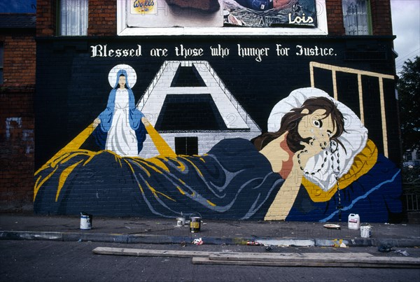 Ireland, North, Belfast, Nationalist Mural of Hunger strike in H Block freshly painted with the paint tins on the pavement in front on the corner of Falls Road.