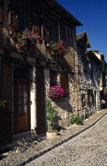 France, Aquitaine, Bergerac, Row or terrace of stone houses with wooden window shutters and hanging flower baskets.