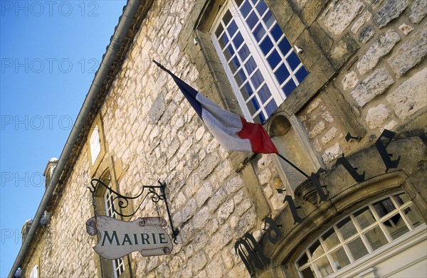 France, Aquitaine, Villefranche-du-Perigord, Mairie Town Hall stone building with French Tricolour flag on flagpole attached to building wall.