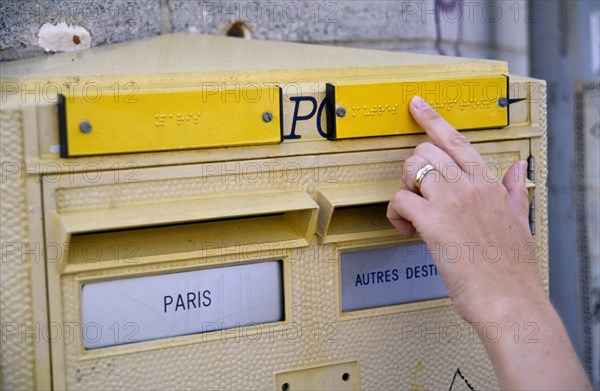 France, Ile de France, Paris, Letter post box with Braille incription for the blind and a female hand reading the raised text.