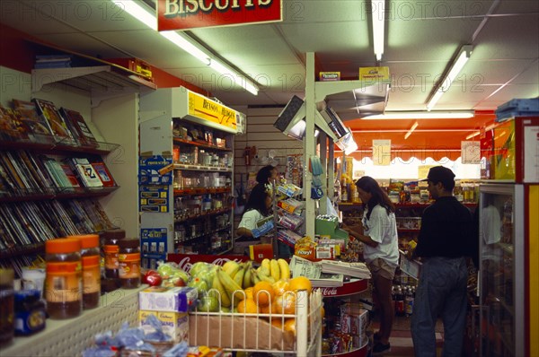 England, East Sussex, Brighton, Staff behind the counter of a corner grocery shop serving customers.