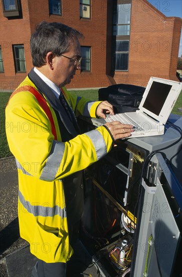 England, West Sussex, Shoreham-by-sea, IT Technician programming traffic lights signal box from a laptop computer.