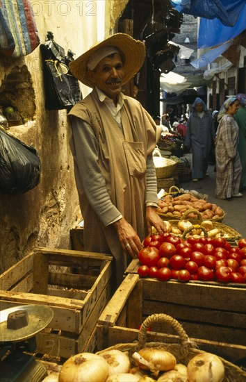 MOROCCO, Fez, Male stallholder behind crates of produce at the fruit market in the souk, pair of scales in the foreground.