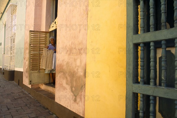 CUBA, Trinidad, Old woman standing in a doorway selling lace garment.