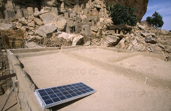 Mali, Pays Dogon, Yaye, Soalr panel on flat rooftop with rock escarpment behind.