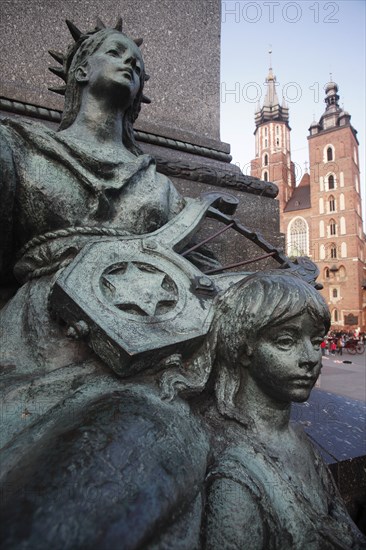 Poland, Krakow, Detail of female figure & child on monument to the polish romantic poet Adam Mickiewicz by Teodor Rygier in 1898 in the Rynek Glowny market square with Mariacki Basilica or Church of St Mary in the background.
