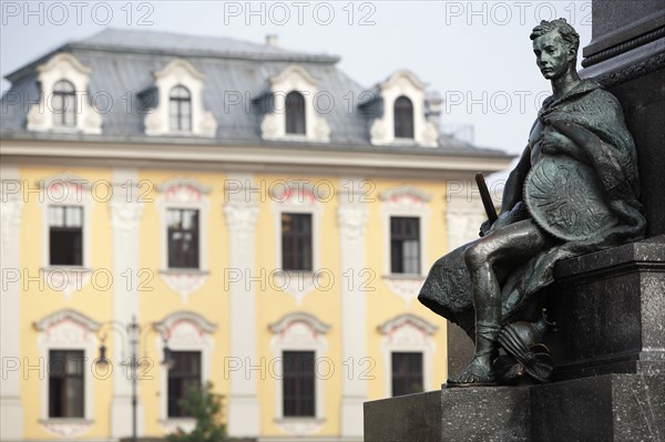 Poland, Krakow, Detail of male figure on monument to the polish romantic poet Adam Mickiewicz by Teodor Rygier in 1898 in the Rynek Glowny market square with pastel coloured building in the background.