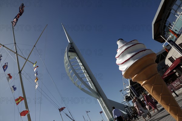 England, Hampshire, Portsmouth, Old Town, Gun Wharf Quay, Spinnaker tower and naval mast with flags blwoing in the wind next to plastic ice cream cone.