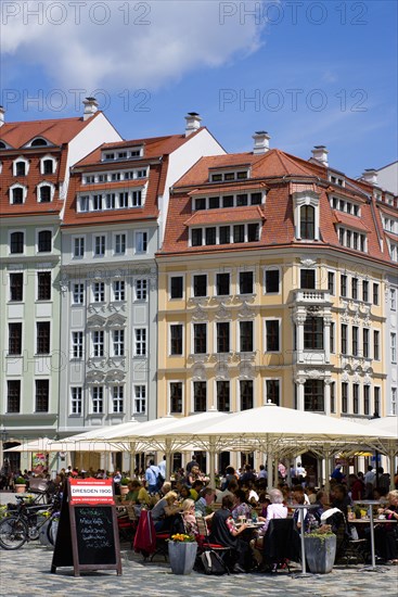 GERMANY, Saxony, Dresden, People sitting at reastaurant cafe tables under umbrellas in Neumarkt beside restored buildings in the square.