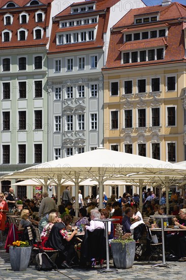 GERMANY, Saxony, Dresden, People sitting at restaurant cafe tables under umbrellas in Neumarkt beside restored buildings in the square.