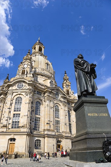 GERMANY, Saxony, Dresden, The restored Baroque church of Frauenkirch Church of Our Lady in Neumarkt with a statue of Martin Luther in the foreground and sightseeing tourists walking in the square.