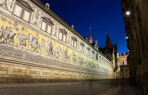 GERMANY, Saxony, Dresden, Fürstenzug or Procession of the Dukes illuminated at sunset in Auguststrasse a mural on 25,000 Meissen tiles that depicts 35 noblemen from the 12th century Konrad the Great, to Friedrich August III, Saxony's last king, who ruled from 1904-1918. It was originally painted by Wilhelm Walter between 1870 and 1876 but eventually, the stucco began to crumble and around 1906-07 it was replaced by the tiles.