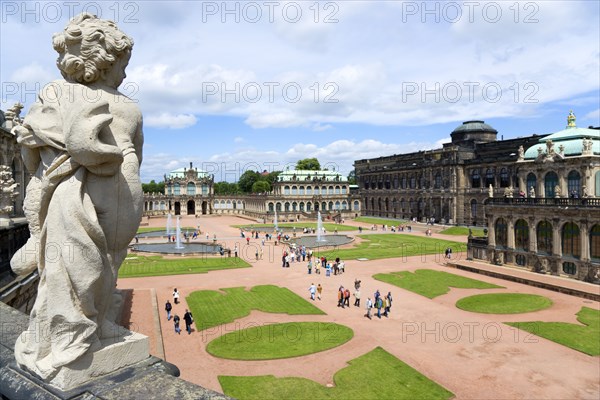 GERMANY, Saxony, Dresden, The central Courtyard of the restored Baroque Zwinger Palace gardens busy with tourists seen from the statue lined Rampart originally built between 1710 and 1732 after a design by Matthäus Daniel Pöppelmann in collaboration with sculptor Balthasar Permoser with the Rampart Pavilion on the left and the Picture Gallery on the right.