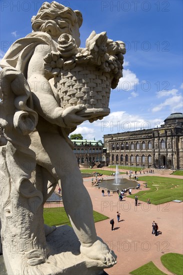 GERMANY, Saxony, Dresden, The central Courtyard and Picture Gallery of the restored Baroque Zwinger Palace gardens busy with tourists seen from the statue lined Rampart originally built between 1710 and 1732 after a design by Matthäus Daniel Pöppelmann in collaboration with sculptor Balthasar Permoser.