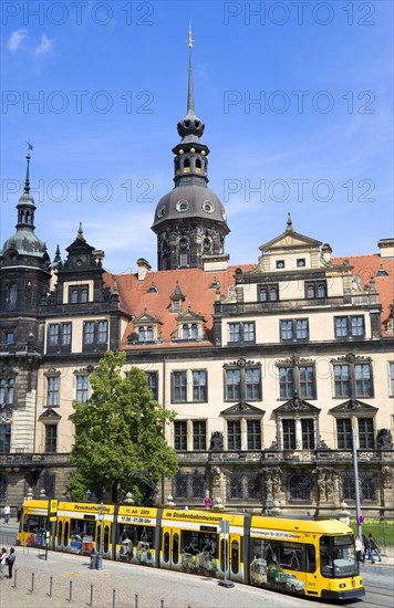 GERMANY, Saxony, Dresden, A yellow tram in the road in front of the Residenzschloss with people walking on sidewalk pavement.