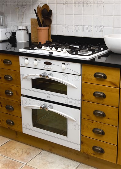 Architecture, Interiors, Kitchen, White domestic gas hob and electric oven household appliance set under worktop in fitted integrated kitchen.