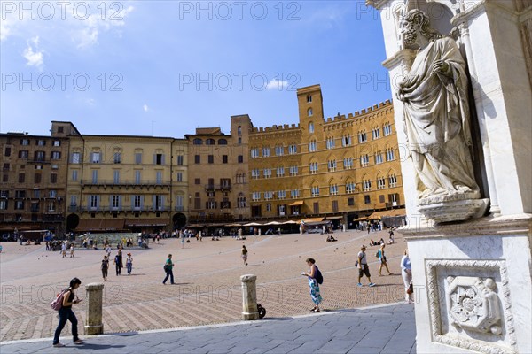 ITALY, Tuscany, Siena, A religious carving on the entrance portico of the Gothic Palazzo Publico town hall with tourists in the Piazza del Campo.