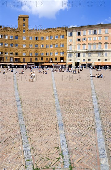 ITALY, Tuscany, Siena, The Piazza del Campo and surrounding buildings with tourists walking in the square.