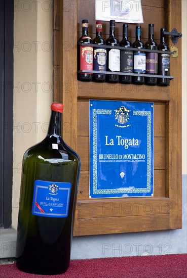 ITALY, Tuscany, Montalcino, Val D'Orcia Brunello di Montalcino Enoteca or wine shop with dispaly of Chianti wines on the pavement around its entrance.