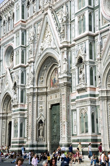 ITALY, Tuscany, Florence, The Neo-Gothic marble west facade of the Cathedral of Santa Maria del Fiore the Duomo with sightseeing tourists sitting on the steps.