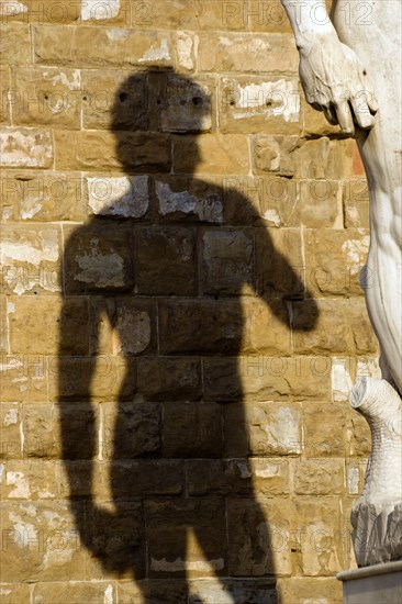 ITALY, Tuscany, Florence, Shadow of the replica Rennaisance statue of David by Michelangelo on the wall of the Palazzo Vecchio in the Piazza della Signoria.