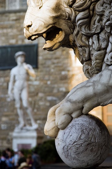 ITALY, Tuscany, Florence, Replica of Rennaisance statue of David by Michelangelo in the Piazza della Signoria beside the Palazzo Vecchio beyond statue of lion with paw on cannonball.