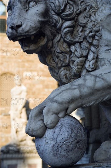 ITALY, Tuscany, Florence, The 1533 statue of Hercules and Cacus by Bandinelli seen through the legs of a stone lion outside the Loggia del Lancia or di Orcagna beside the Palazzo Vecchio in the Piazza della Signoria with a stone lion in the foreground.